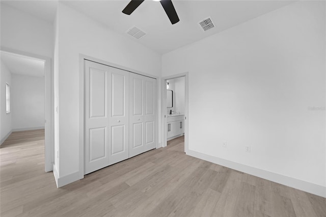 unfurnished bedroom featuring a closet, ceiling fan, ensuite bathroom, and light hardwood / wood-style flooring