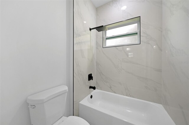 bathroom with tiled shower / bath combo and toilet