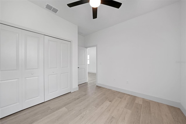 unfurnished bedroom featuring a ceiling fan, visible vents, baseboards, light wood-style floors, and a closet