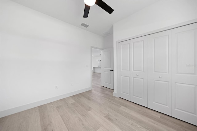 unfurnished bedroom featuring lofted ceiling, light hardwood / wood-style flooring, ceiling fan, and a closet