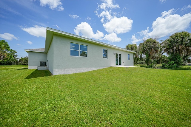 back of house with stucco siding and a lawn