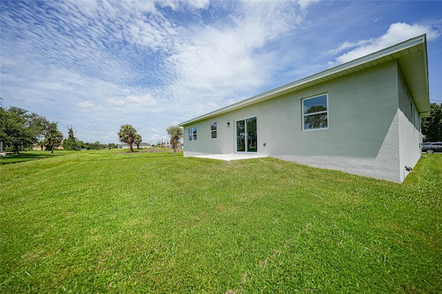 back of house featuring a patio, a yard, and stucco siding