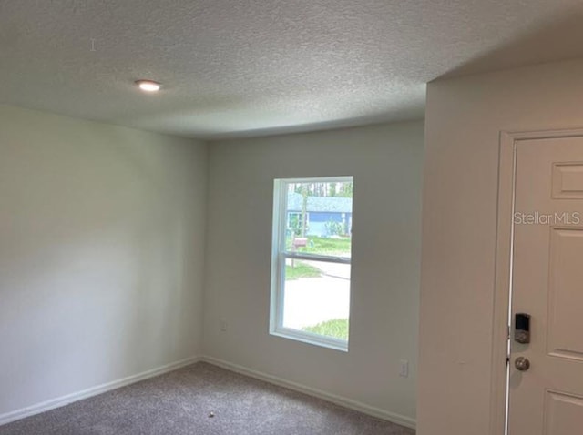 carpeted empty room with a textured ceiling