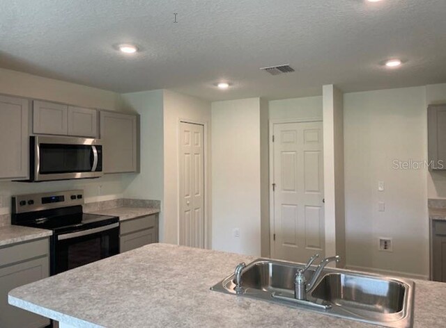 kitchen with appliances with stainless steel finishes, a textured ceiling, and sink