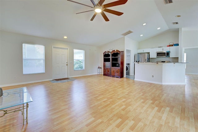 living room with lofted ceiling, light hardwood / wood-style flooring, ceiling fan, and washer / dryer