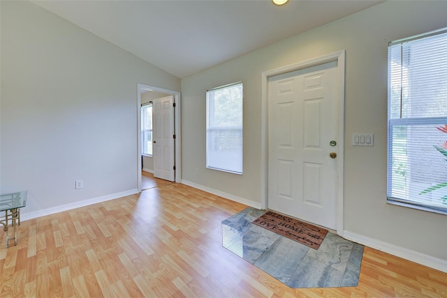 foyer featuring vaulted ceiling, a wealth of natural light, and light hardwood / wood-style floors