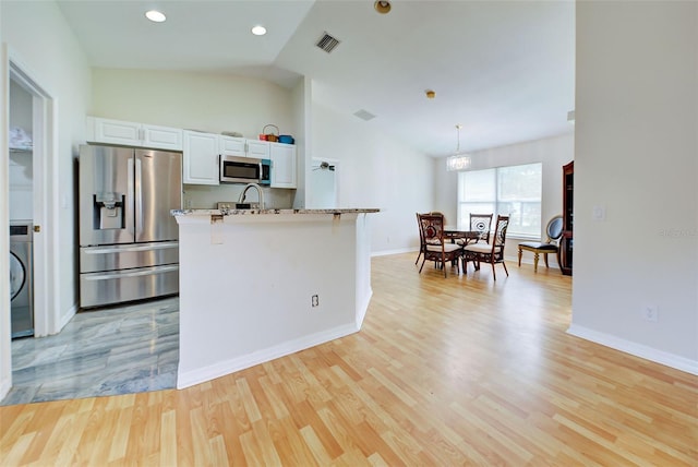 kitchen featuring light wood-type flooring, decorative light fixtures, stainless steel appliances, light stone counters, and white cabinets