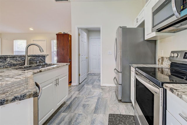 kitchen featuring stone countertops, stainless steel appliances, sink, and white cabinets