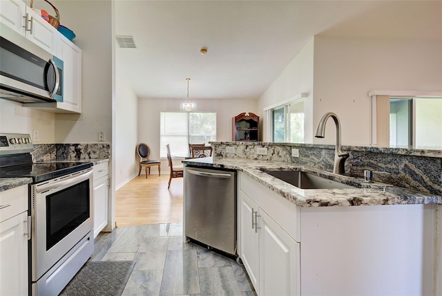 kitchen featuring white cabinetry, sink, appliances with stainless steel finishes, lofted ceiling, and light hardwood / wood-style floors