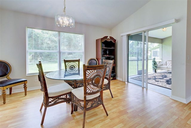 dining area featuring light hardwood / wood-style flooring, vaulted ceiling, and an inviting chandelier