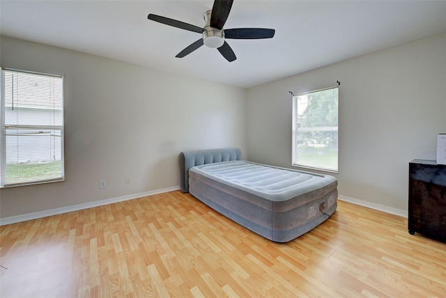 bedroom with multiple windows, wood-type flooring, and ceiling fan