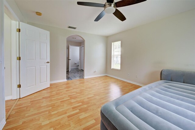 bedroom featuring light wood-type flooring, ceiling fan, and ensuite bath