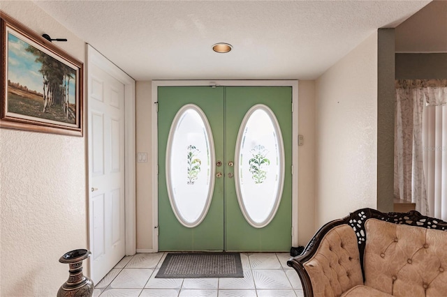 foyer entrance featuring a textured ceiling, light tile patterned floors, and french doors