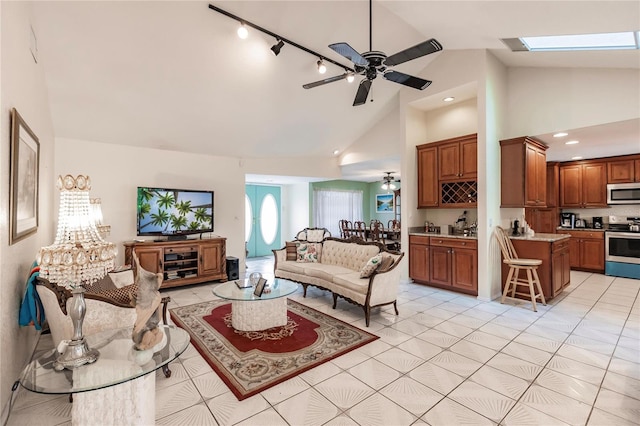 living room featuring light tile patterned floors, high vaulted ceiling, a skylight, rail lighting, and ceiling fan