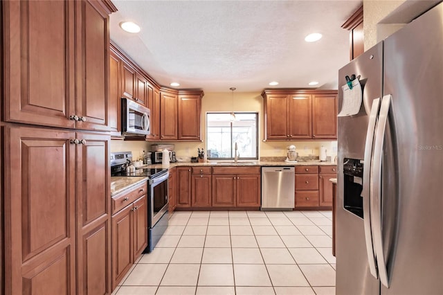 kitchen with decorative light fixtures, light tile patterned floors, stainless steel appliances, sink, and light stone counters