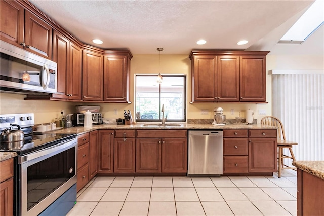 kitchen with appliances with stainless steel finishes, hanging light fixtures, sink, a skylight, and light tile patterned flooring