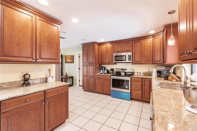 kitchen featuring pendant lighting, stainless steel appliances, sink, and light tile patterned floors