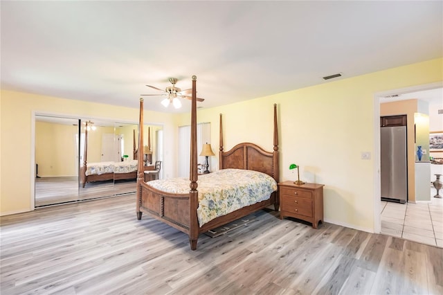 bedroom with ceiling fan, stainless steel fridge, and light wood-type flooring