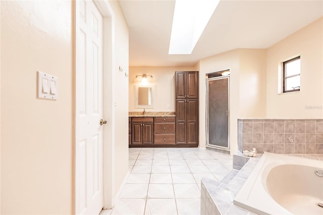 bathroom featuring tile patterned flooring, vanity, shower with separate bathtub, and a skylight