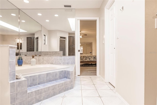 bathroom featuring tiled tub, ceiling fan, and tile patterned floors