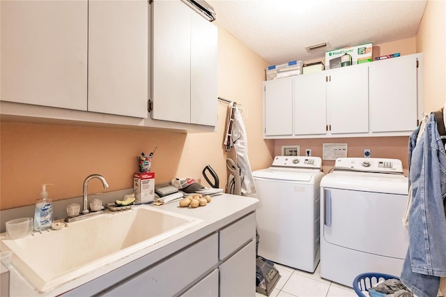 laundry room featuring light tile patterned floors, cabinets, separate washer and dryer, and sink