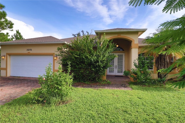 view of front of property with a garage, french doors, and a front lawn