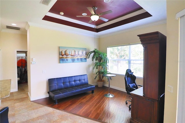 home office featuring crown molding, light hardwood / wood-style flooring, ceiling fan, and a raised ceiling