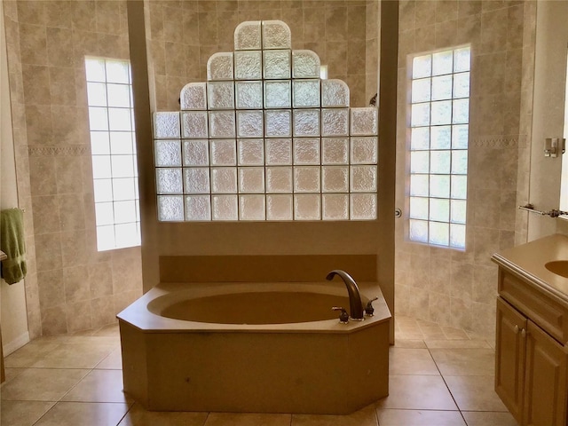 bathroom with tile patterned flooring, tile walls, a tub to relax in, and vanity