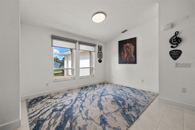 spare room featuring lofted ceiling and light tile patterned flooring