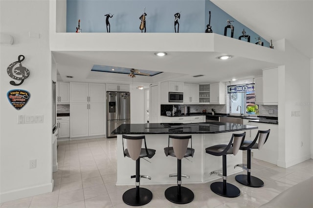 kitchen featuring stainless steel appliances, light tile patterned flooring, white cabinets, and a breakfast bar area