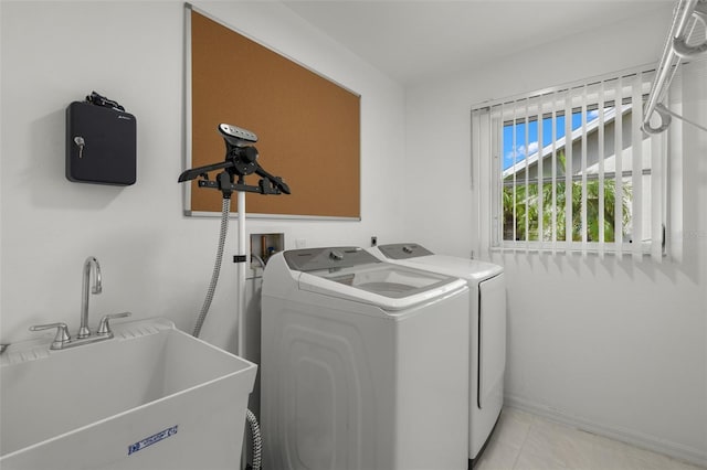 laundry area with light tile patterned floors, washer and dryer, and sink