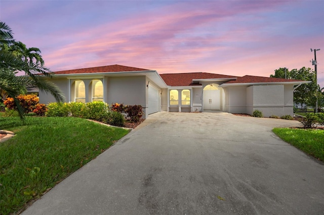 view of front facade with a front lawn, driveway, an attached garage, and stucco siding