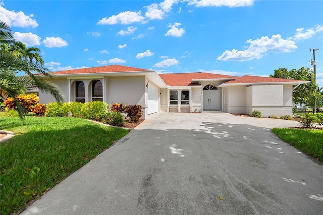 view of front facade with a front yard, driveway, an attached garage, and stucco siding