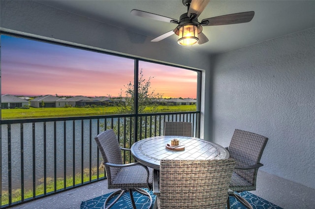 sunroom with ceiling fan and a water view