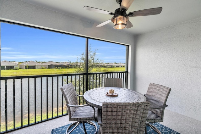 sunroom / solarium with ceiling fan and a water view