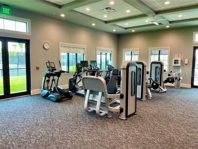 workout area with carpet floors, a high ceiling, coffered ceiling, and ceiling fan