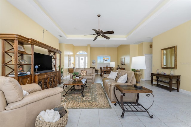 tiled living room with ceiling fan and a tray ceiling