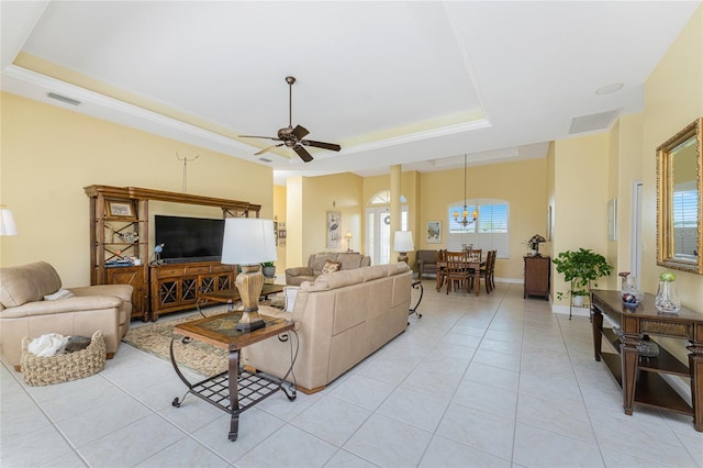 living room featuring ceiling fan with notable chandelier, light tile patterned floors, and a raised ceiling