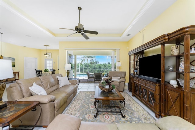 living room featuring a raised ceiling, ceiling fan, and light tile patterned flooring