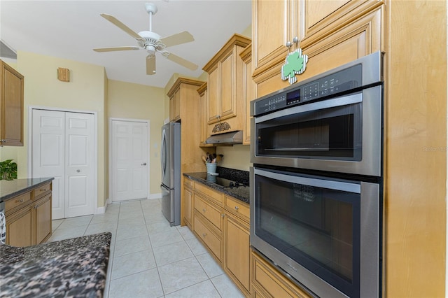 kitchen with ceiling fan, dark stone countertops, stainless steel appliances, and light tile patterned flooring