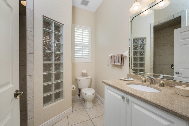 bathroom with tile patterned flooring, vanity, toilet, and tiled shower