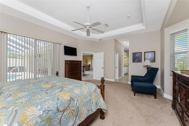 bedroom featuring ensuite bath, light colored carpet, a tray ceiling, access to exterior, and ceiling fan