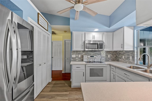 kitchen with white cabinets, stainless steel appliances, sink, lofted ceiling, and wood-type flooring