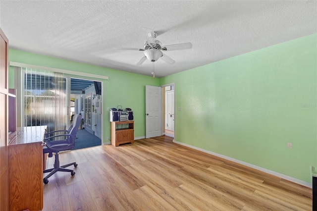 home office with ceiling fan, light hardwood / wood-style floors, and a textured ceiling