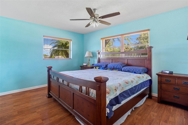 bedroom featuring ceiling fan, multiple windows, and dark hardwood / wood-style flooring