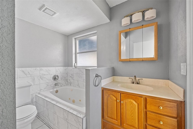 bathroom with tiled tub, toilet, tile patterned floors, vanity, and a textured ceiling