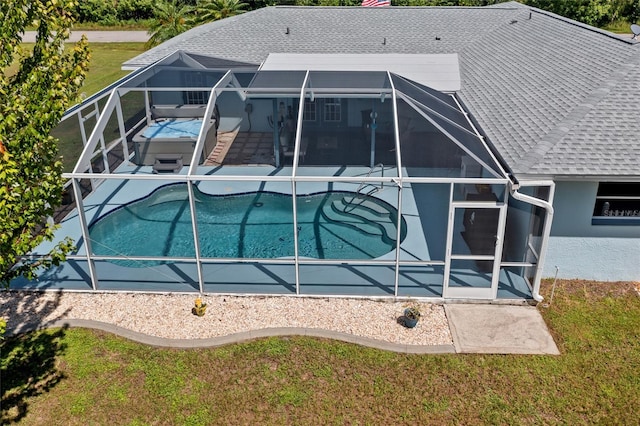 rear view of house with a yard, glass enclosure, and a patio area