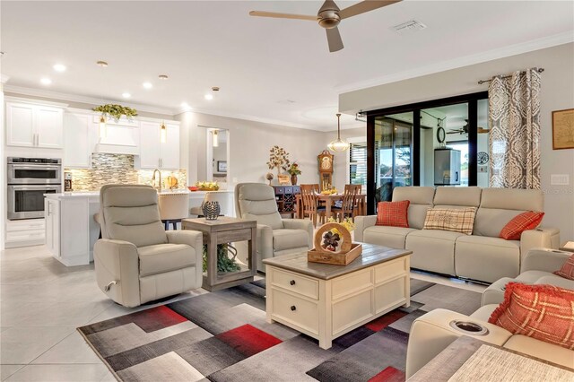 living room with ornamental molding, light tile patterned flooring, and ceiling fan