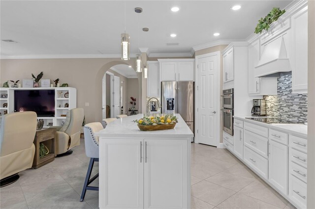 kitchen featuring a breakfast bar area, an island with sink, hanging light fixtures, stainless steel appliances, and white cabinetry