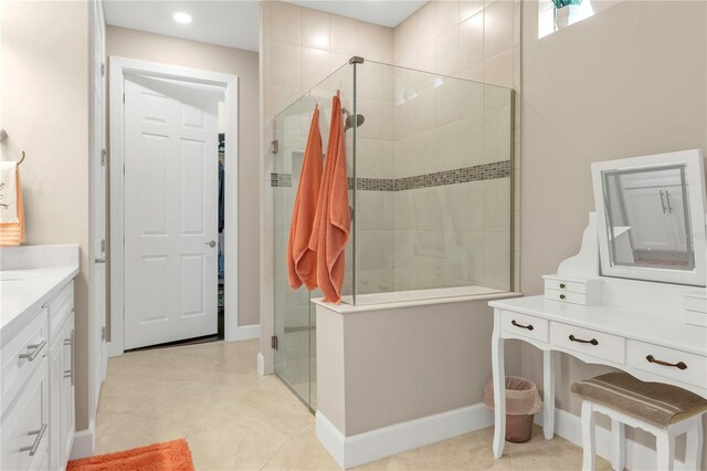 bathroom featuring tile patterned flooring, a tile shower, and vanity